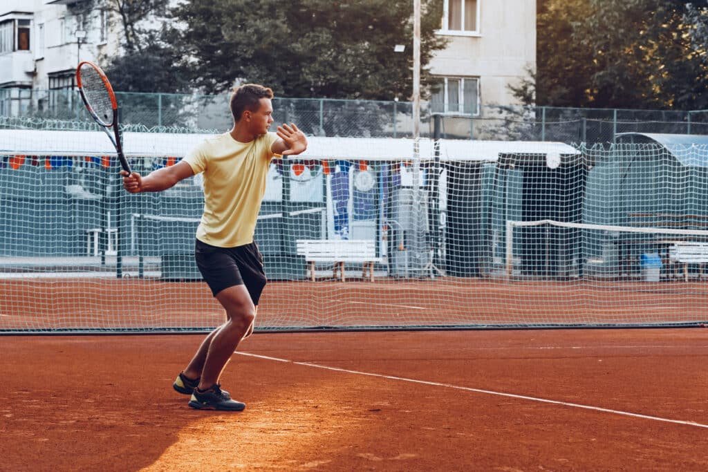 Young handsome man playing tennis on the tennis court