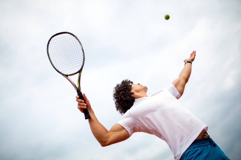 Young handsome tennis player with racket and ball prepares to serve at beginning of game or match