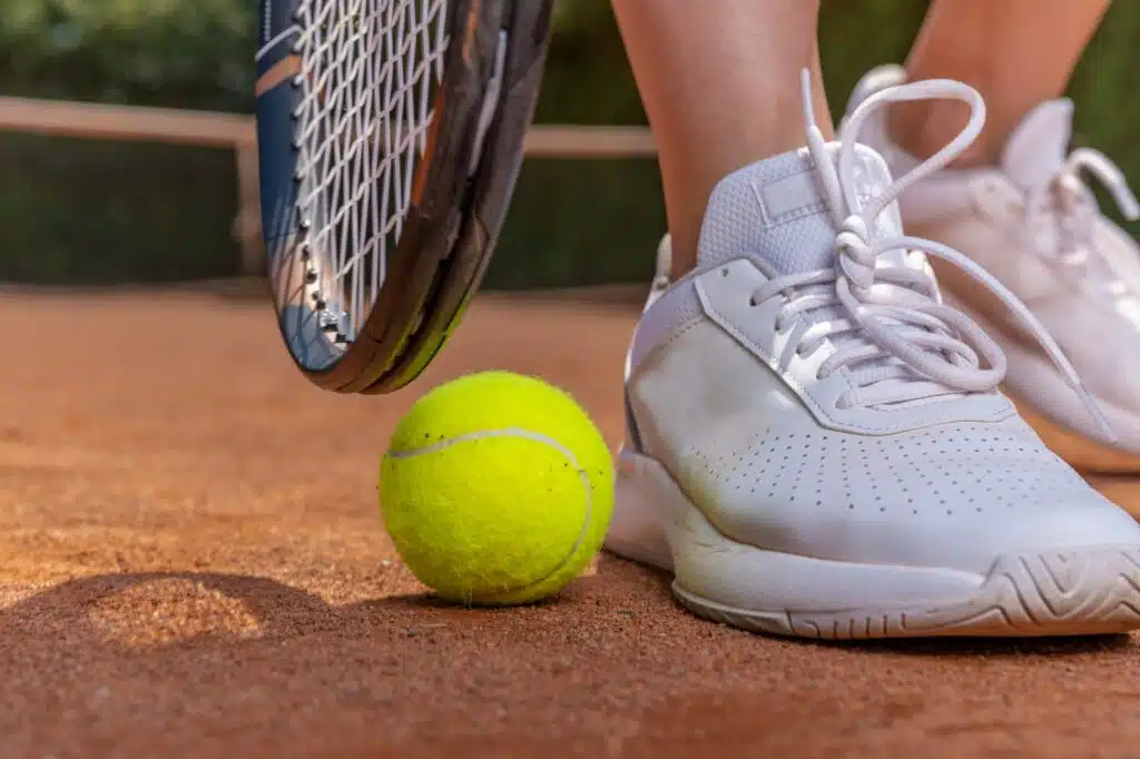 close-up on tennis player on court, racket, ball and shoes