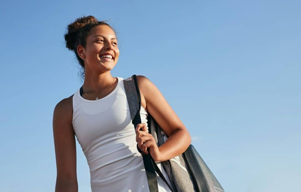 Happy female tennis player with bag