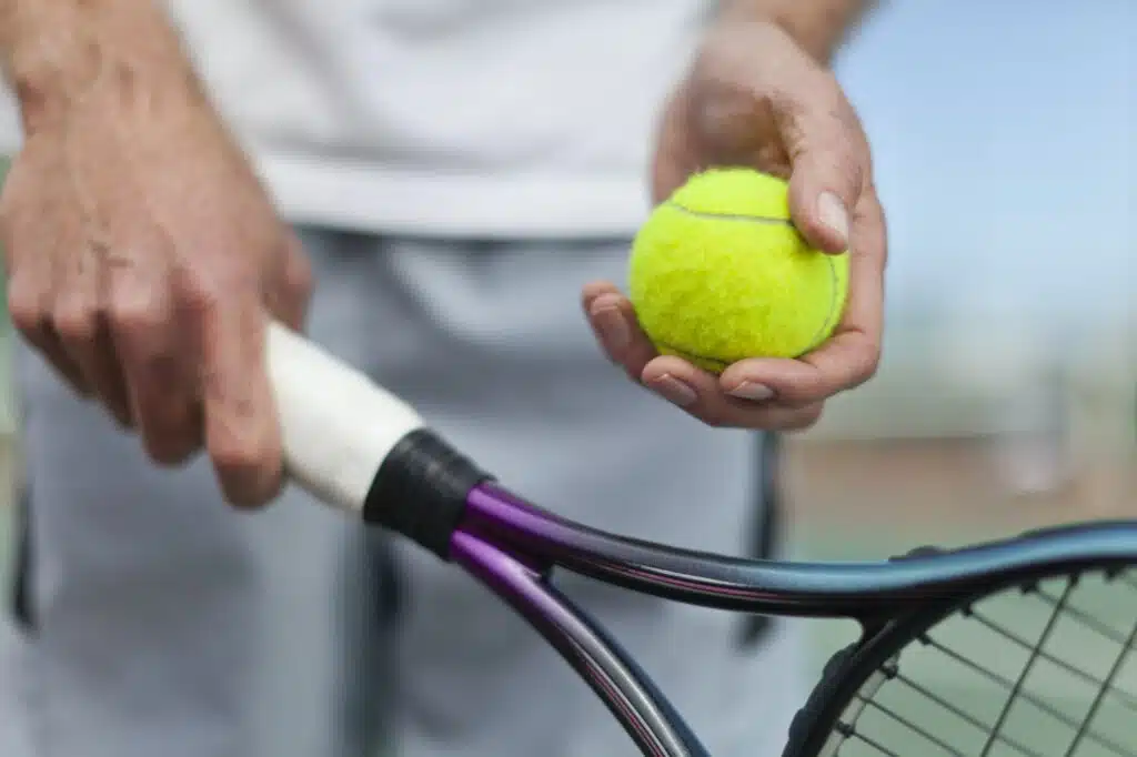 Older man holding tennis ball and racket