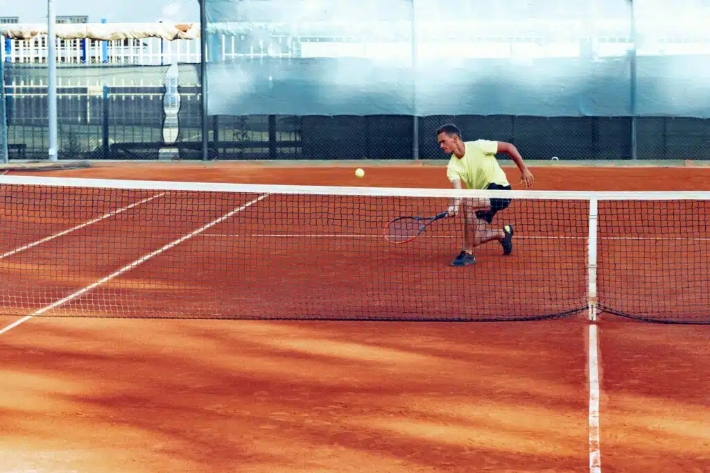 Young handsome man playing tennis on the tennis court