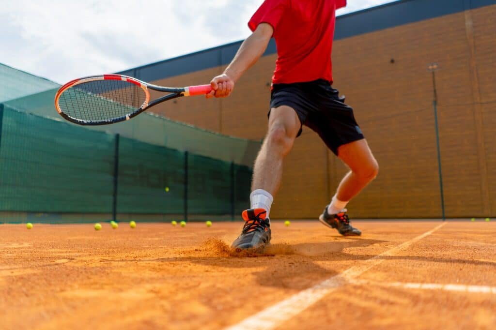 young professional player coach on tennis court practicing strokes with racket and tennis ball