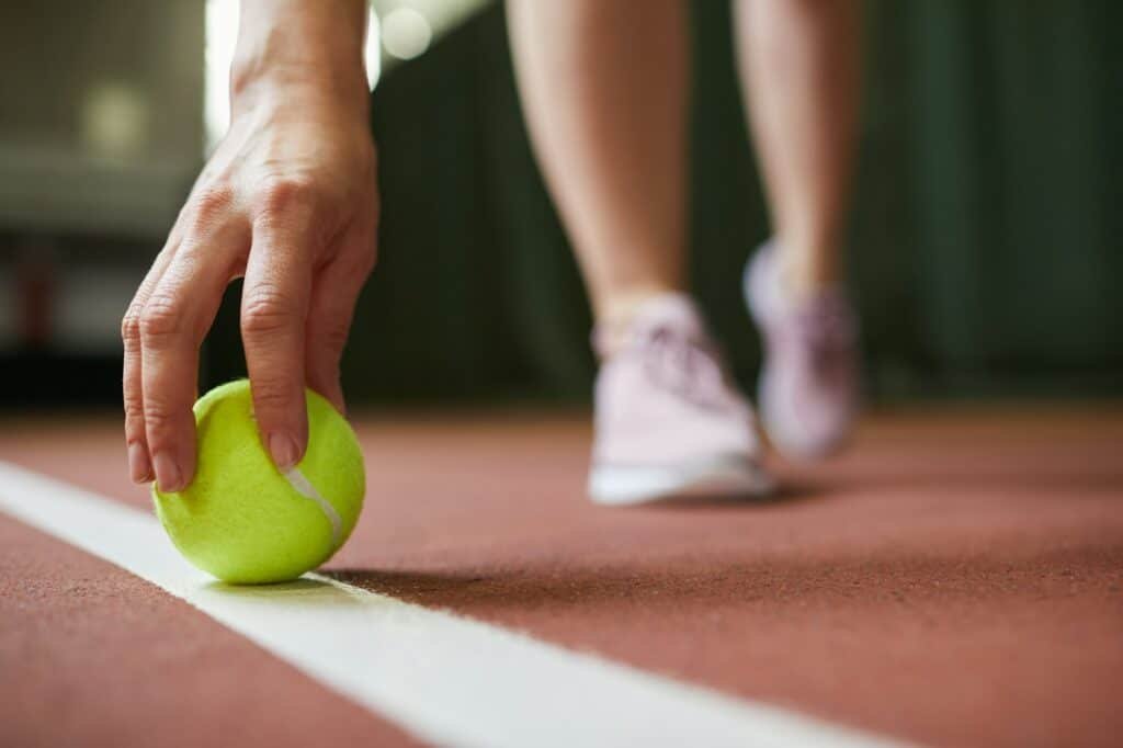 Putting tennis ball on baseline