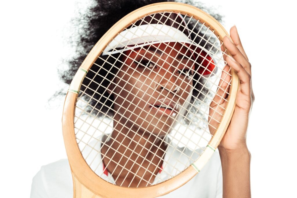 close-up portrait of young female tennis player holding racket in front of face isolated on white