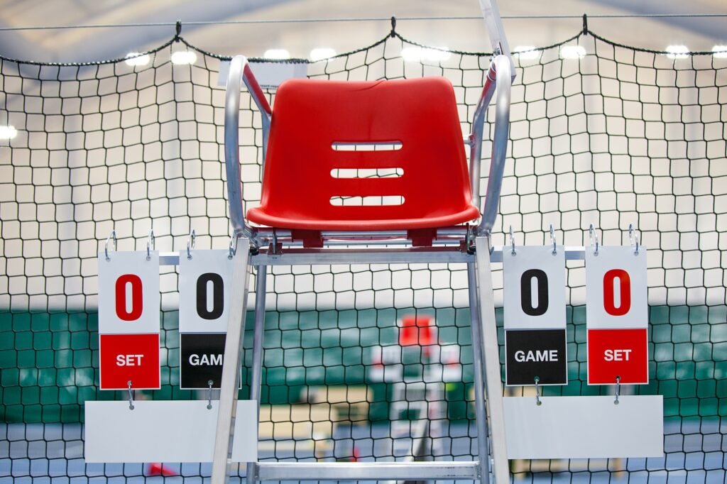 Umpire chair with scoreboard on a tennis court before the game.